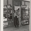 Migrant family emerging from grocery store where they have stopped along the road in order to buy bread and potatoes, which will form the basis for their noonday meal. Near Henryetta, Oklahoma