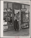 Migrant family emerging from grocery store where they have stopped along the road in order to buy bread and potatoes, which will form the basis for their noonday meal. Near Henryetta, Oklahoma