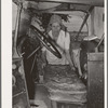 Mrs. Elmer Thomas, migrant to California, putting the front seat of their truck in place preparatory to departure from Muskogee, Oklahoma