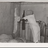 Interior of migrant's home near Muskogee, with mother removing articles of clothing preparatory for departure to California. Oklahoma