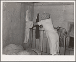 Interior of migrant's home near Muskogee, with mother removing articles of clothing preparatory for departure to California. Oklahoma