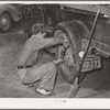 Tightening the rear wheel on truck which will carry migrant family to California from Muskogee, Oklahoma