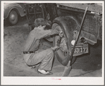 Tightening the rear wheel on truck which will carry migrant family to California from Muskogee, Oklahoma