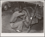 Tightening the rear wheel on truck which will carry migrant family to California from Muskogee, Oklahoma