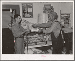 Head of migrant family buying loaf of bread in grocery store of small town near Henryetta, Oklahoma