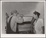 Migrant man and woman at rear of their truck before departure for California from Muskogee, Oklahoma