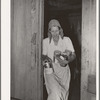 Mrs. Elmer Thomas, migrant to California, removing the spices, coffee, etc., to their car from their home which they are preparing to leave. Near Muskogee, Oklahoma