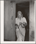 Mrs. Elmer Thomas, migrant to California, removing the spices, coffee, etc., to their car from their home which they are preparing to leave. Near Muskogee, Oklahoma