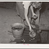Daughter of tenant farmer living near Muskogee, Oklahoma, changing water in goldfish bowl. Refer to general caption number 20