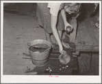 Daughter of tenant farmer living near Muskogee, Oklahoma, changing water in goldfish bowl. Refer to general caption number 20