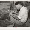 Resident of Mays Avenue camp taking out a piece of glass from boy's foot. Oklahoma City, Oklahoma