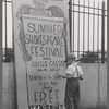 Boy standing next to Summer Shakespeare Festival poster at the East River Park Amphitheatre prior to a New York Shakespeare Festival production of Julius Caesar