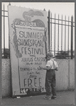 Boy standing next to Summer Shakespeare Festival poster at the East River Park Amphitheatre prior to a New York Shakespeare Festival production of Julius Caesar