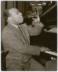 Count Basie seated at piano with Coca-Cola bottle