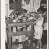 Child at cluttered table in shack home in Mays Avenue camp. Oklahoma City, Oklahoma
