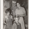 Woman in shack home in community camp. Oklahoma City, Oklahoma. Straightening her son's hair