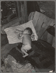 Baby with his bottle in shack home near Mays Avenue camp. Oklahoma City, Oklahoma