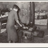 Woman preparing breakfast in shack home. Mays Avenue camp, Oklahoma City, Oklahoma