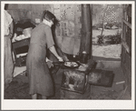Woman preparing breakfast in shack home. Mays Avenue camp, Oklahoma City, Oklahoma