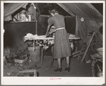 Woman ironing in tent home. Community camp, Oklahoma City, Oklahoma