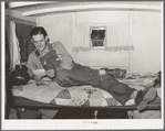 Oil field worker in his trailer home reading a letter. Seminole, Oklahoma