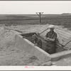 Mr. Shoenfeldt and son, FSA (Farm Security Administration) client in Sheridan County, Kansas, at entrance to fruit cellar which they built for six dollars and twenty cents