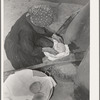 Spanish-American woman removing freshly baked bread from outdoor earthen oven near Taos, New Mexico