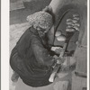 Spanish-American woman removing baked bread from outdoor earthen oven by means of a long wooden paddle. Near Taos, New Mexico