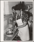 Spanish-American woman peeling peppers after the skins were loosened by heating on top of stove. Near Taos, New Mexico