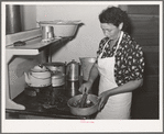 Spanish-American woman removing peppers from stove. Taos, New Mexico