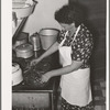 Spanish-American woman placing and turning peppers on the stove near Taos, New Mexico