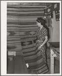 WPA (Works Progress Administartion/Work Projects Administration) project supervisor displaying some of the articles made at her weaving project. Costilla, New Mexico
