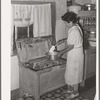 Spanish-American woman taking flour from old-type flour bin in her home near Taos, New Mexico