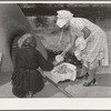 Wiping ashes from freshly-baked bread which has just been removed from earthen oven. Spanish-American farm home near Taos, New Mexico