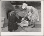 Wiping ashes from freshly-baked bread which has just been removed from earthen oven. Spanish-American farm home near Taos, New Mexico