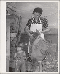 Spanish-American woman and her son with greens which they feed to their rabbits near Taos, New Mexico