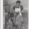 Spanish-American woman and her son with greens which they feed to their rabbits near Taos, New Mexico