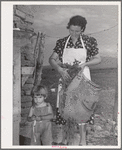 Spanish-American woman and her son with greens which they feed to their rabbits near Taos, New Mexico