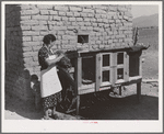 Spanish-American FSA (Farm Security Administration) client feeding her rabbits near Taos, New Mexico