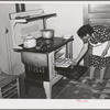 Spanish-American woman removing baked bread from oven farm near Taos, New Mexico