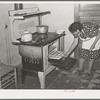 Spanish-American woman removing baked bread from oven farm near Taos, New Mexico