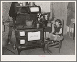 Sitting by the kitchen stove on a cold autumn day in New England. Near Bradford, Vermont, Orange County