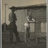Ted Shawn standing with man outdoors and washing hands under water tap with bucket
