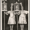 Unidentified showgirls [with cockatiels in pole-mounted cages] in the stage production Jumbo