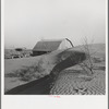 The winds of the "dust bowl" have piled up large drifts of soil against this farmer's barn near Liberal, Kansas