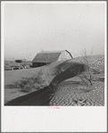 The winds of the "dust bowl" have piled up large drifts of soil against this farmer's barn near Liberal, Kansas