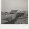 The winds of the "dust bowl" have piled up large drifts of soil against this farmer's barn near Liberal, Kansas