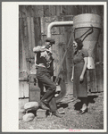 Elmo Temple, Chaffee County, Colorado rehabilitation client and his wife, Louise, pose beside a feed grinder which is an important part of their farm equipment