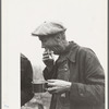 Farmer eats hamburger at cornhusking contest, Marshall County, Iowa