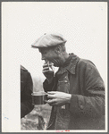 Farmer eats hamburger at cornhusking contest, Marshall County, Iowa